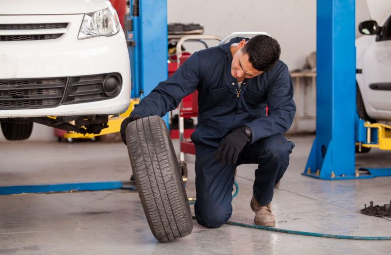 Car mechanic is working on a tire of a car.